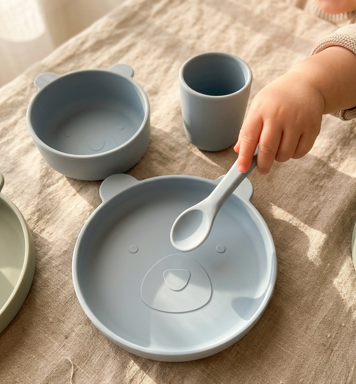 Children's tableware set with bowl, cup, and spoon on a textured surface