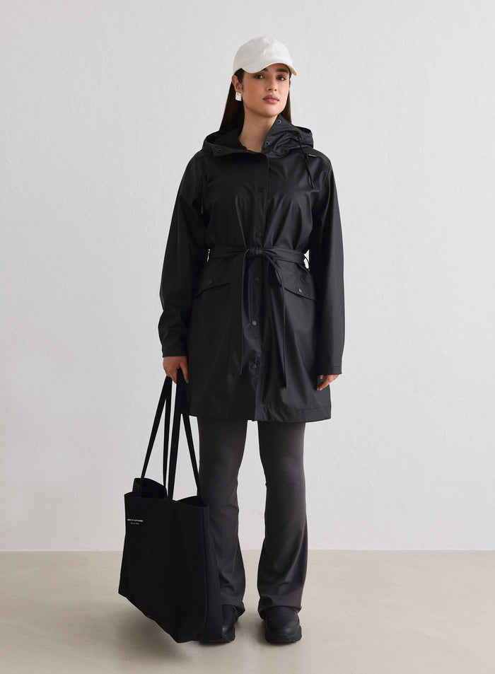 Malli yllään musta aim'n Rain Jacket, valkoinen lippis ja musta tote-laukku [M-174cm]