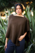 Woman wearing a brown poncho standing among green plants