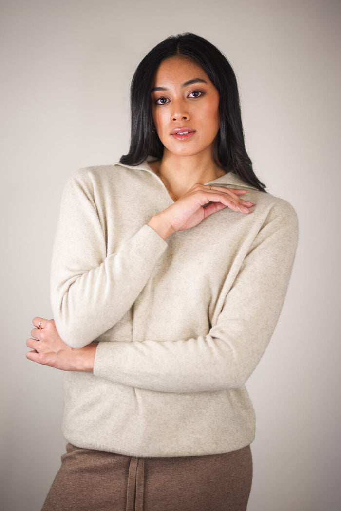 Woman wearing a beige sweater against a plain background
