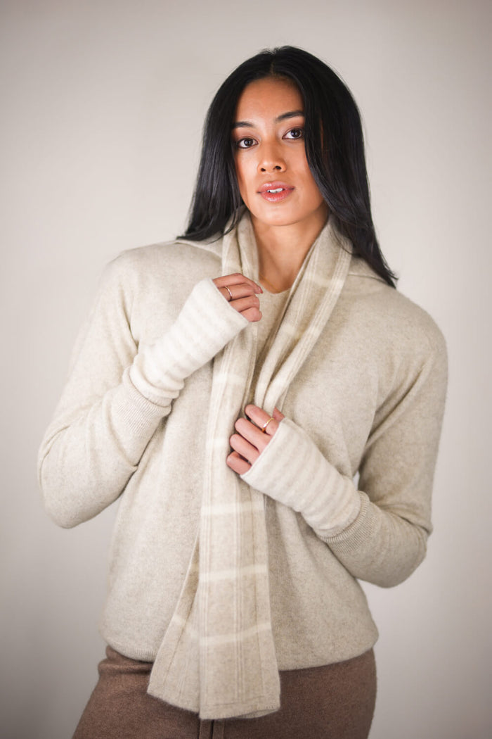 Woman wearing a beige sweater and scarf against a plain background
