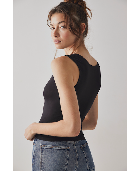 A female model wearing a black scoop-neck sleeveless tank top paired with a denim skirt, side view