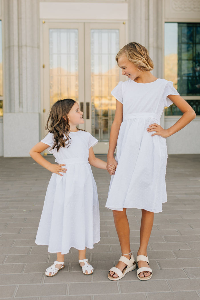 two girls in matching white dresses