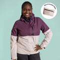 Ela Mo™ Regenjacke | Grape. Eine Frau in einer kompakt faltbaren Regenjacke vor hellgrünem Hintergrund.