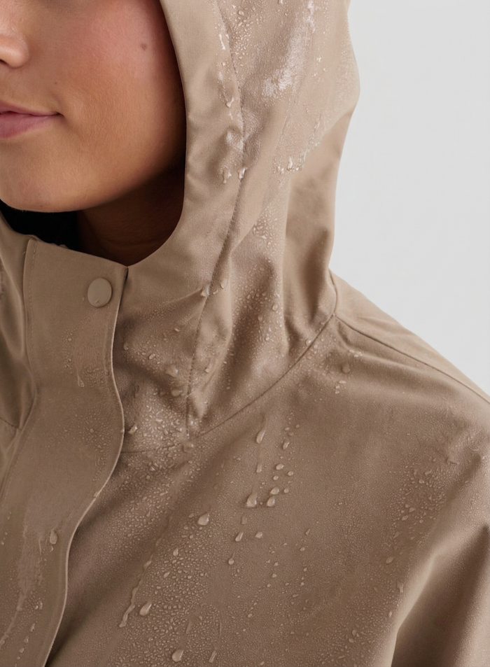 Lähikuva henkilöstä päällään Espresso Waterproof Oversized Anorak -anorakki, jonka hupussa ja kankaassa on vesipisaroita