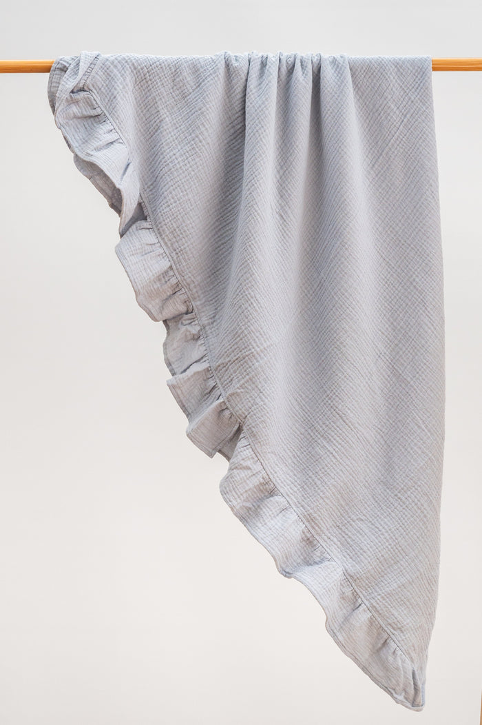 Soft sky blue heirloom ruffle muslin baby blanket folded neatly, made from breathable organic muslin with ruffle edging.