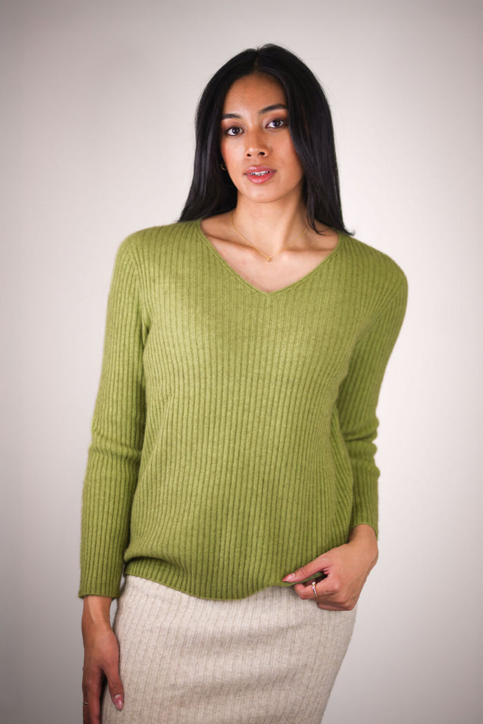 Woman wearing a green sweater against a plain background