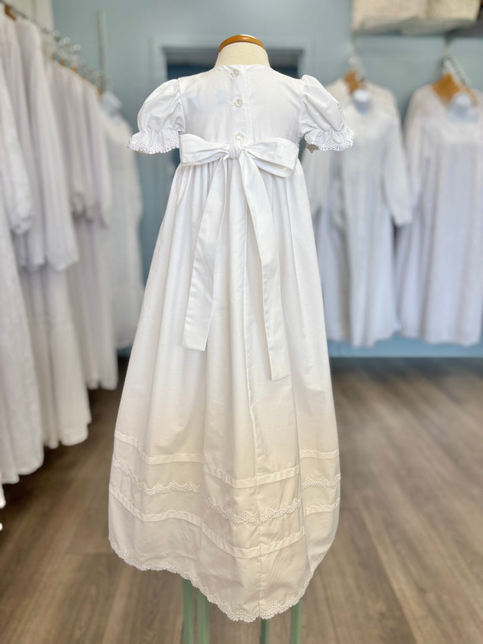 Back of white baby gown with buttons and tie bow.