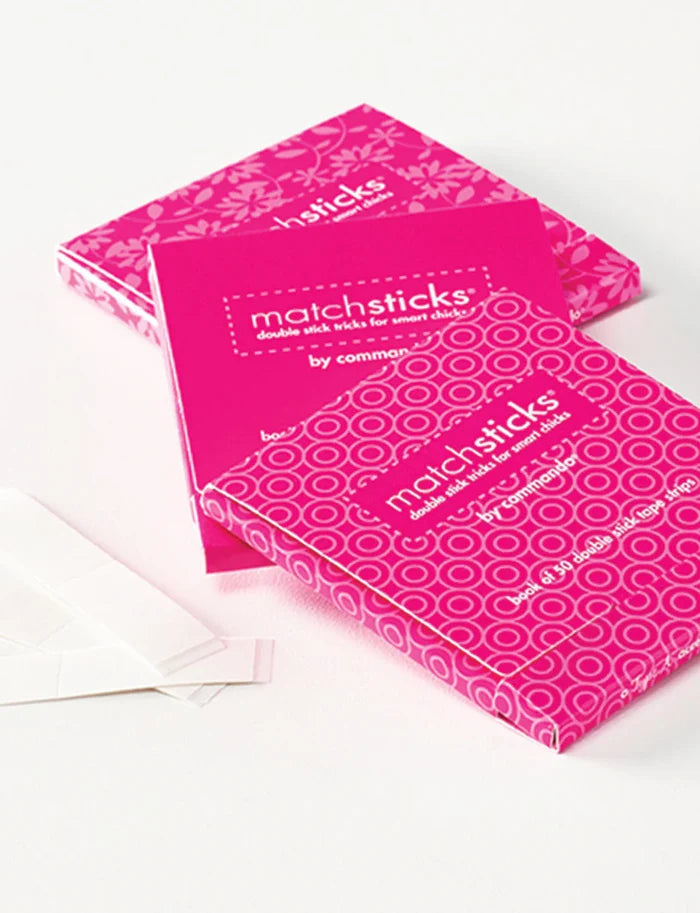 A box of clear double stick tape strips designed for fixing clothing, branded as 'Matchsticks' by Commando.