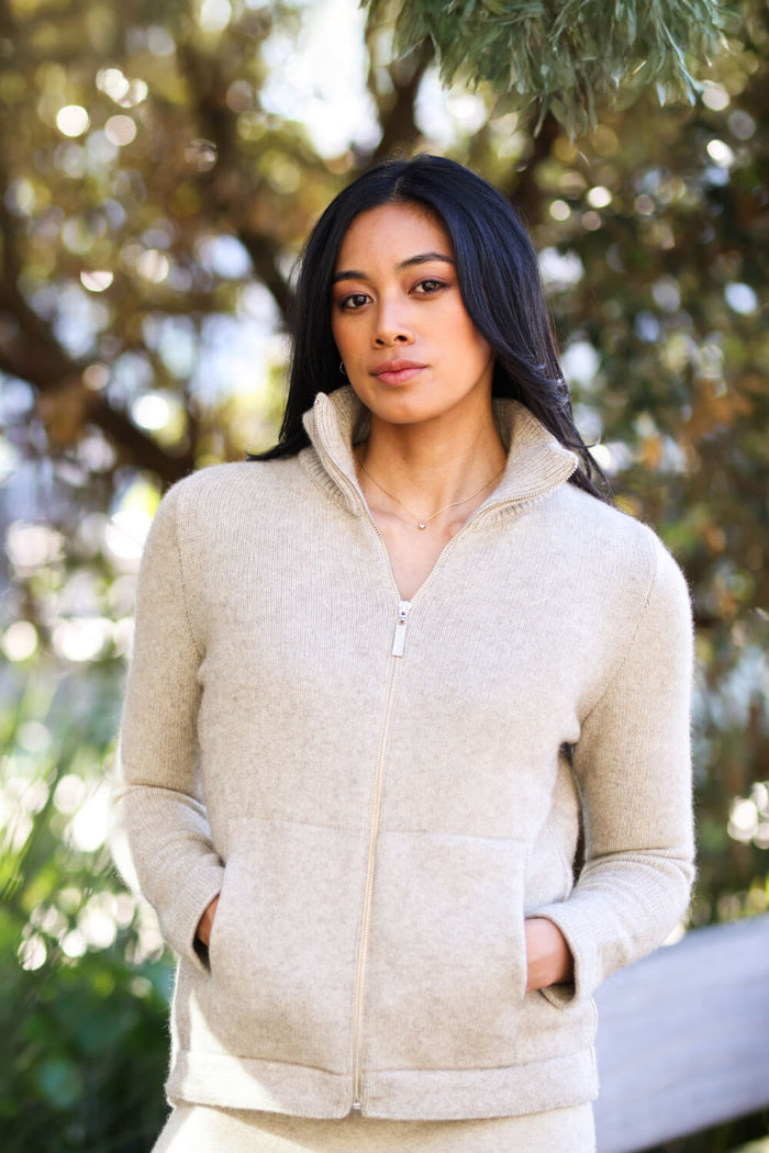 Woman wearing a beige quilted jacket outdoors with trees in the background