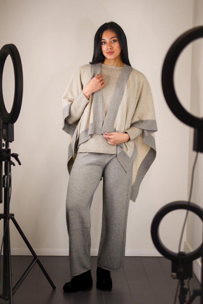 Woman wearing a gray and beige outfit in a studio setting with lighting equipment.