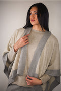 Woman wearing a beige and gray poncho against a plain background