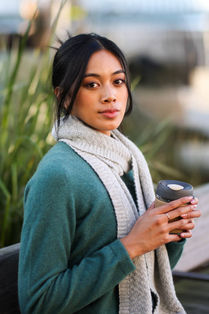 Woman holding a coffee cup outdoors with blurred background
