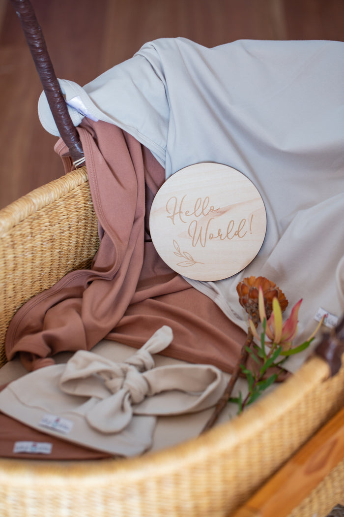 Organic cotton swaddle with jersey beanie baby announcement milestone card 'hello world'.
