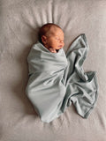Organic jersey swaddle in Mineral, designed as a gentle newborn essential for comfort and connection.