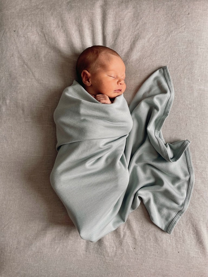 Organic jersey swaddle in Mineral, designed as a gentle newborn essential for comfort and connection.