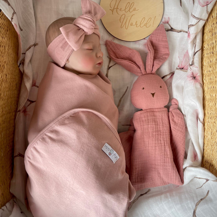 Birth announcement. Newborn baby wrapped in an organic jersey swaddle with matching headband along with a muslin bunny comforter and milestone card reading 'hello world'