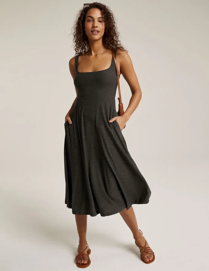 A woman wearing a square neckline, midi length dress with pockets in a spacedye pattern.