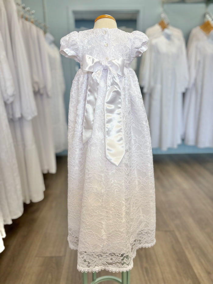 Back of white baby gown with buttons and satin bow.