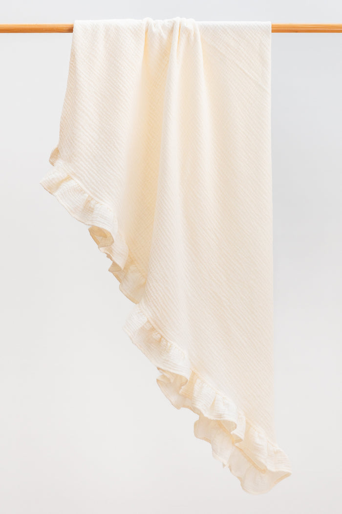 Milk Ivory heirloom ruffle muslin baby blanket folded neatly, featuring soft organic muslin and a delicate ruffle trim.